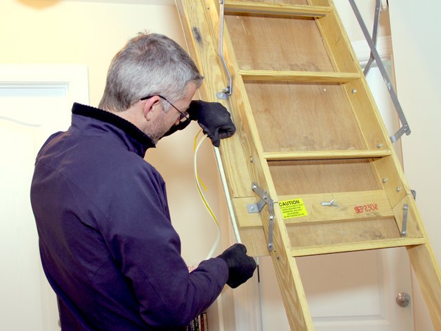 professional-inspecting-attic-pull-down-ladder-safety.png